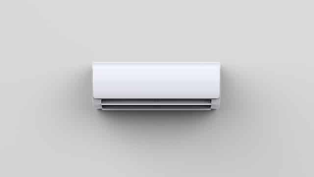Unité intérieure de climatisation murale blanche et moderne, avec des persiennes d'aération, installée sur un mur gris clair.